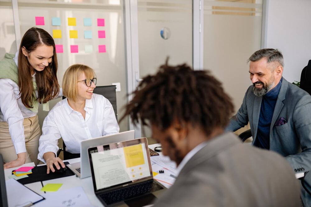 Friendly team collaborating around laptops in a modern office